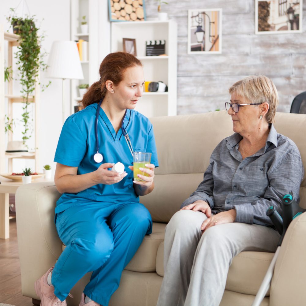 Female doctor talking with senior woman in nursing home about new drug pills